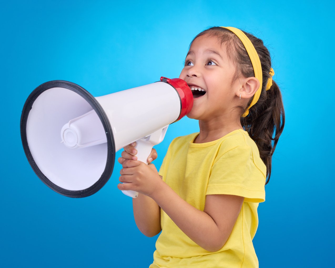 Communication, Speech and Child with Megaphone for News, Opinion and Announcement on Blue Background. Talking, Speaking Mockup and Young Girl with Microphone for Voice, Scream and Attention in Studio